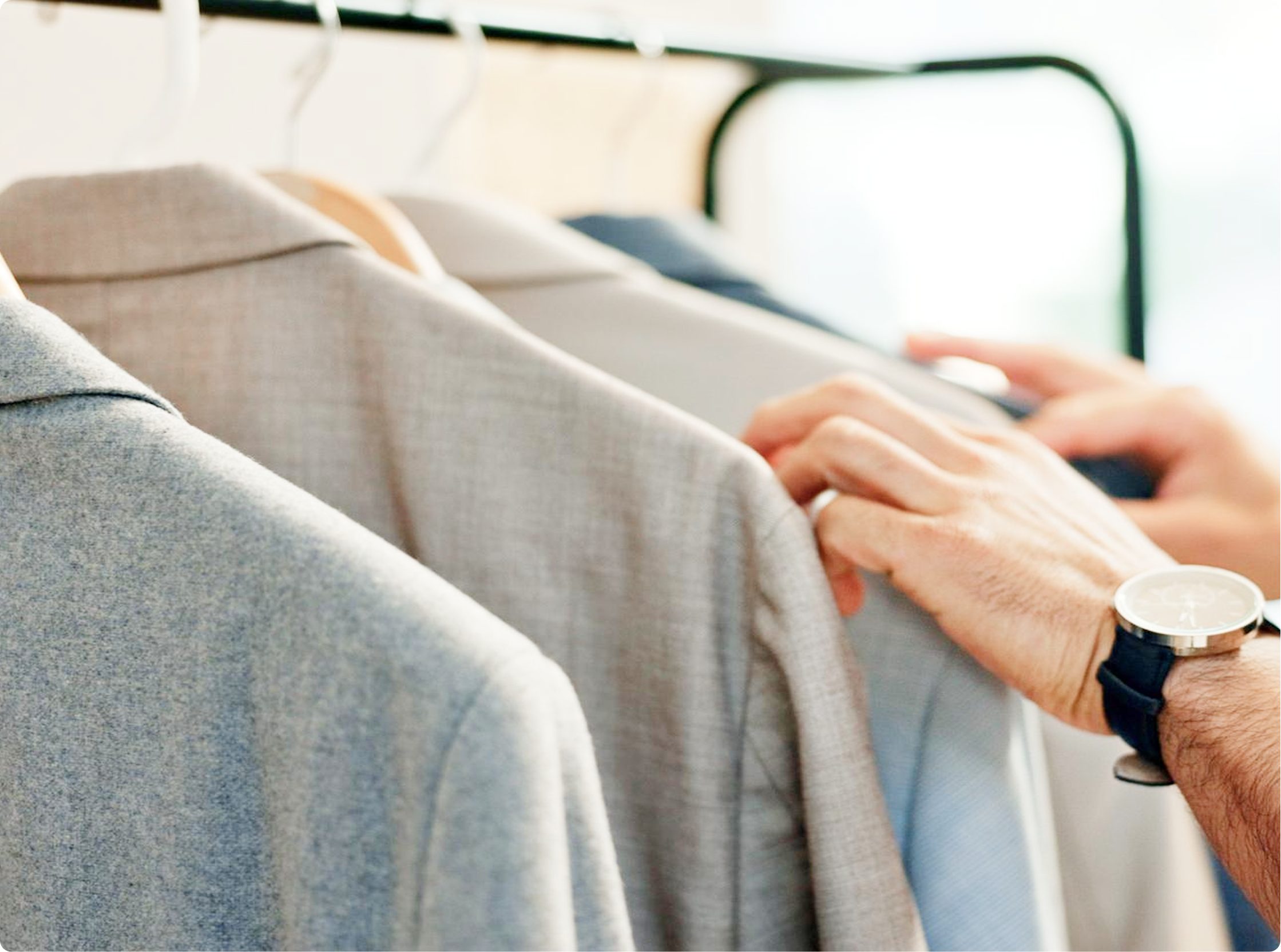 Executive selecting a freshly dry-cleaned shirt from a wardrobe rail of business wear