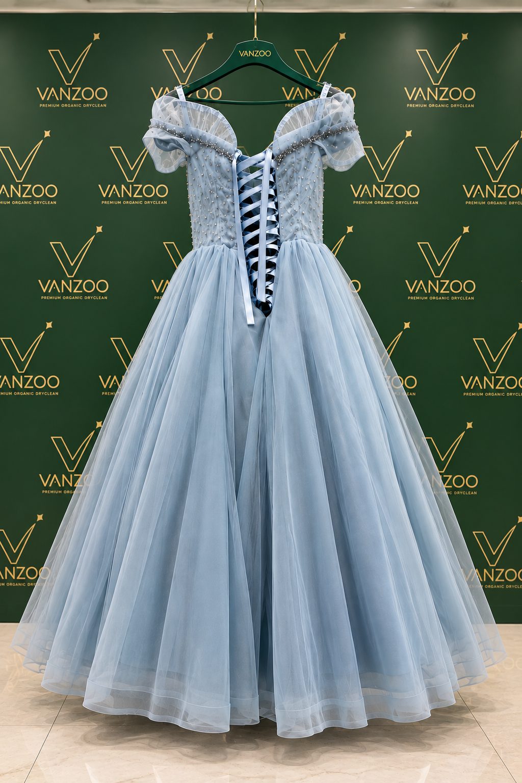 A pale blue gown on display against the Vanzoo branded backdrop