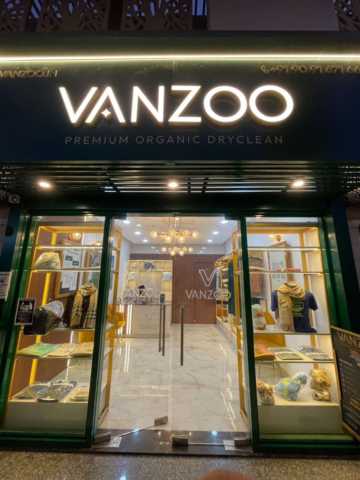 Vanzoo store lit up at night with garments displayed behind the glass front