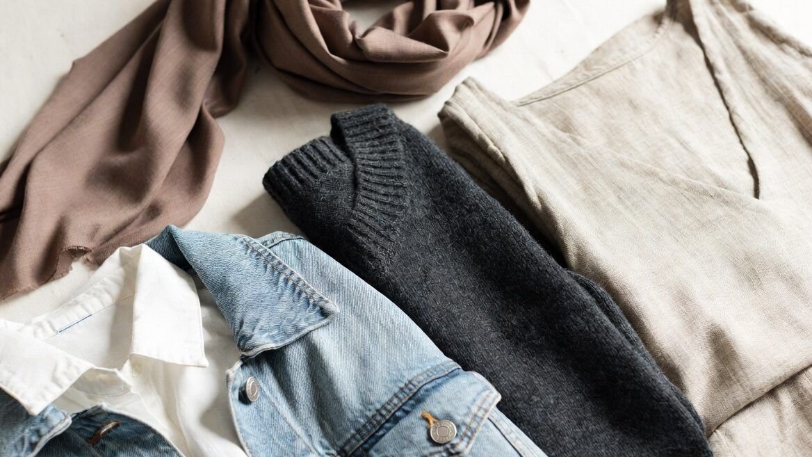 “Flat lay of neatly folded clothes made of different fabrics like cotton, silk, denim, wool, and linen on a neutral background, soft natural lighting, minimal aesthetic, lifestyle photography style, clean and modern”- Different Types of Fabric and How to Care for Them